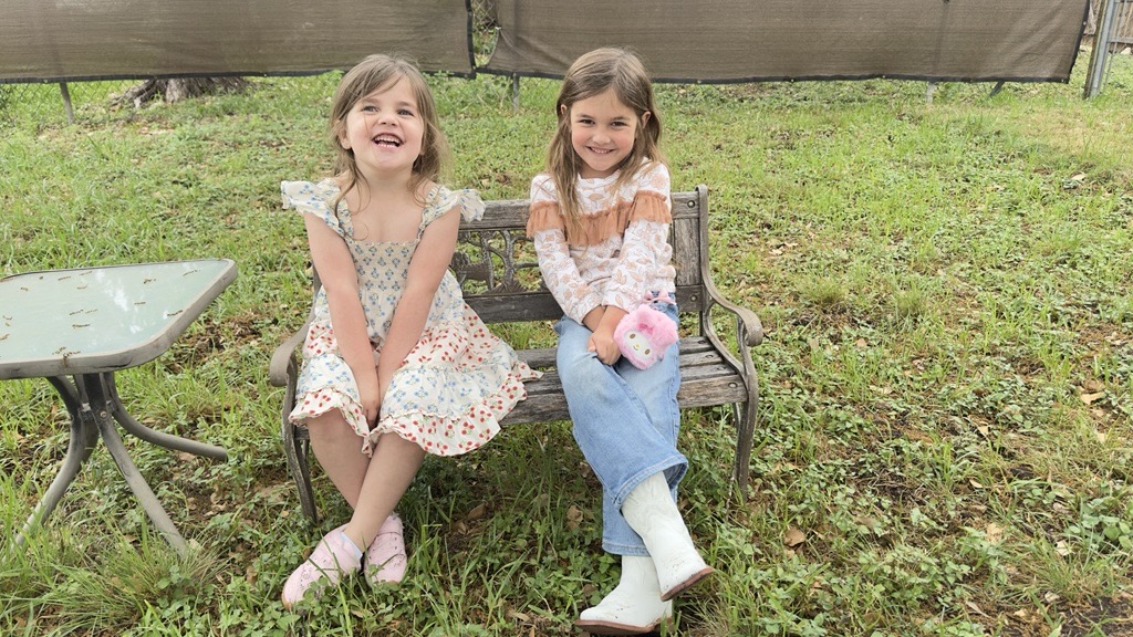 Ruth and Maggie sitting together on a bench in the yard